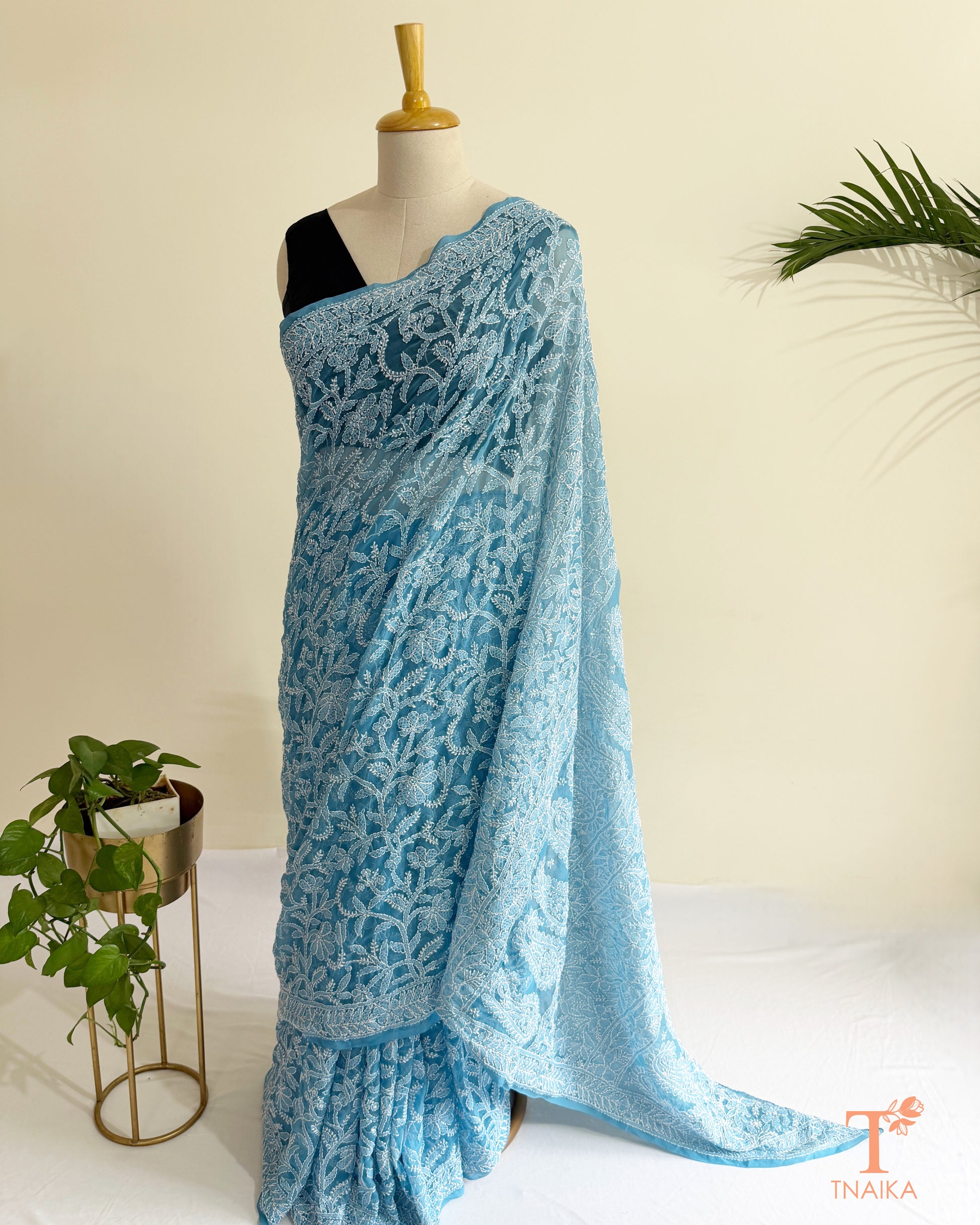 Powder blue Lucknowi Chikankari saree with intricate white floral embroidery and paisley motifs.