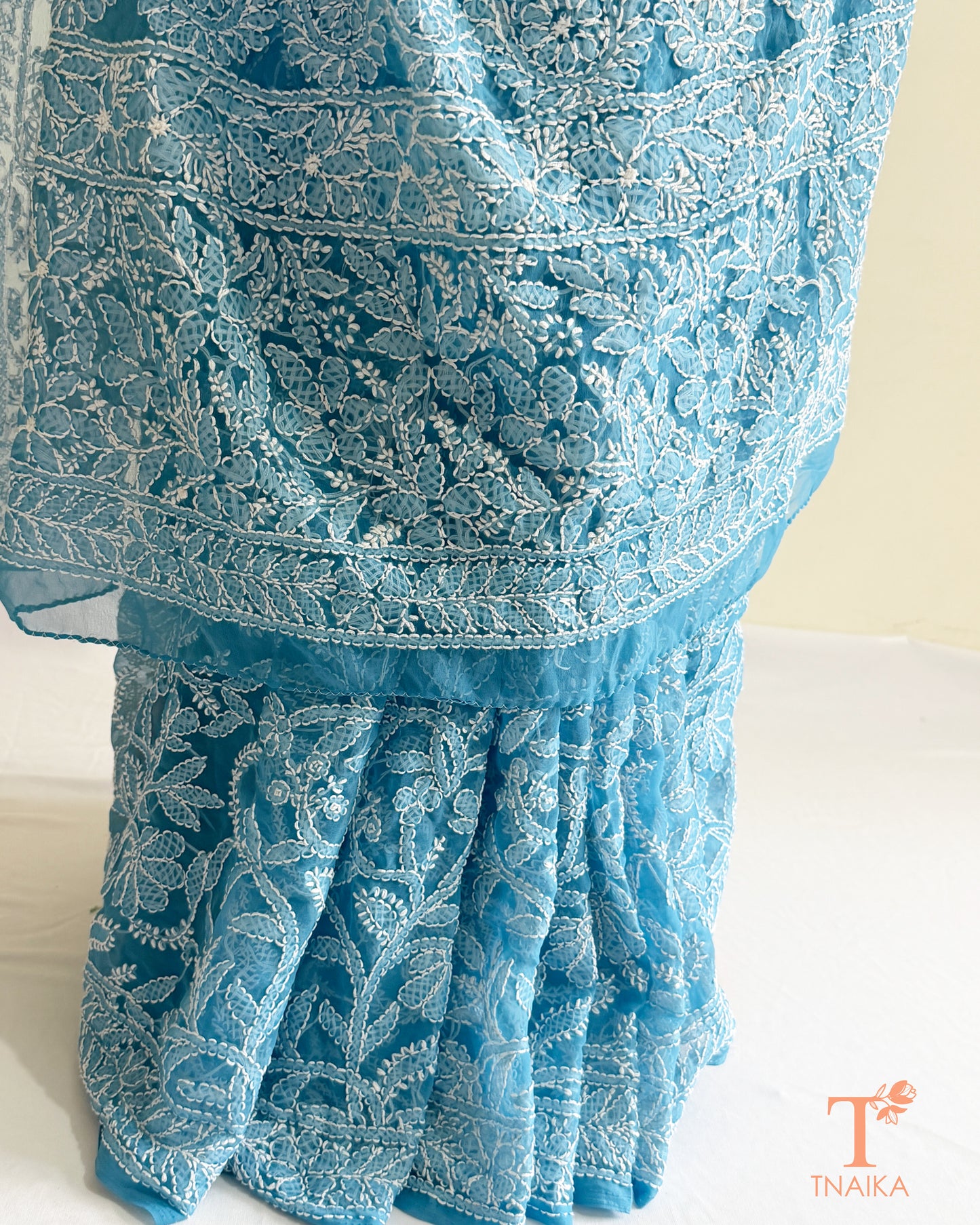 Designer powder blue Lucknowi Chikankari saree with all-over floral embroidery and elegant drape.