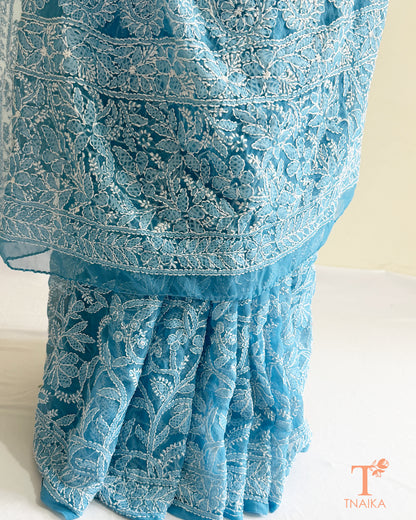 Designer powder blue Lucknowi Chikankari saree with all-over floral embroidery and elegant drape.