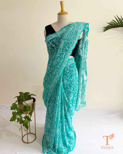 Hand-embroidered turquoise teal Chikankari saree with all-over floral motifs and delicate white threadwork.