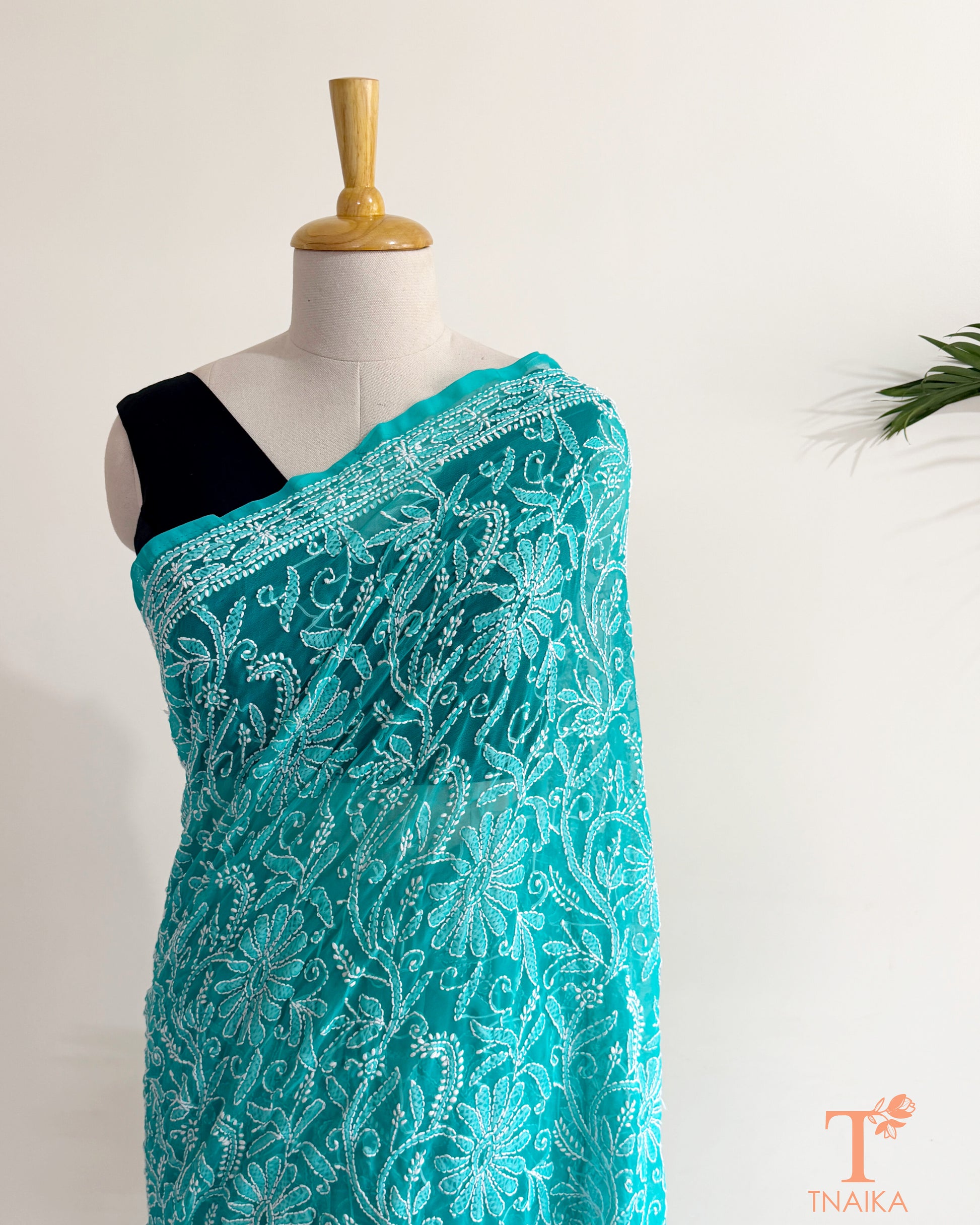Turquoise teal georgette Chikankari saree adorned with handcrafted white floral and vine embroidery.