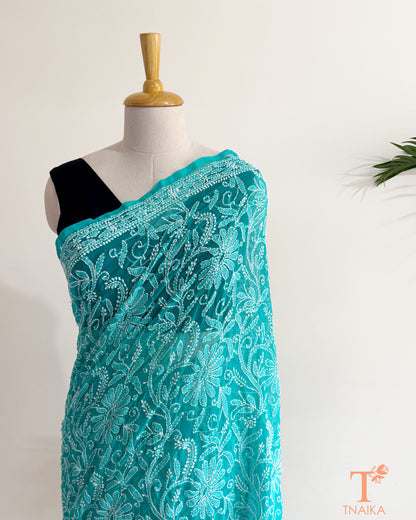 Turquoise teal georgette Chikankari saree adorned with handcrafted white floral and vine embroidery.