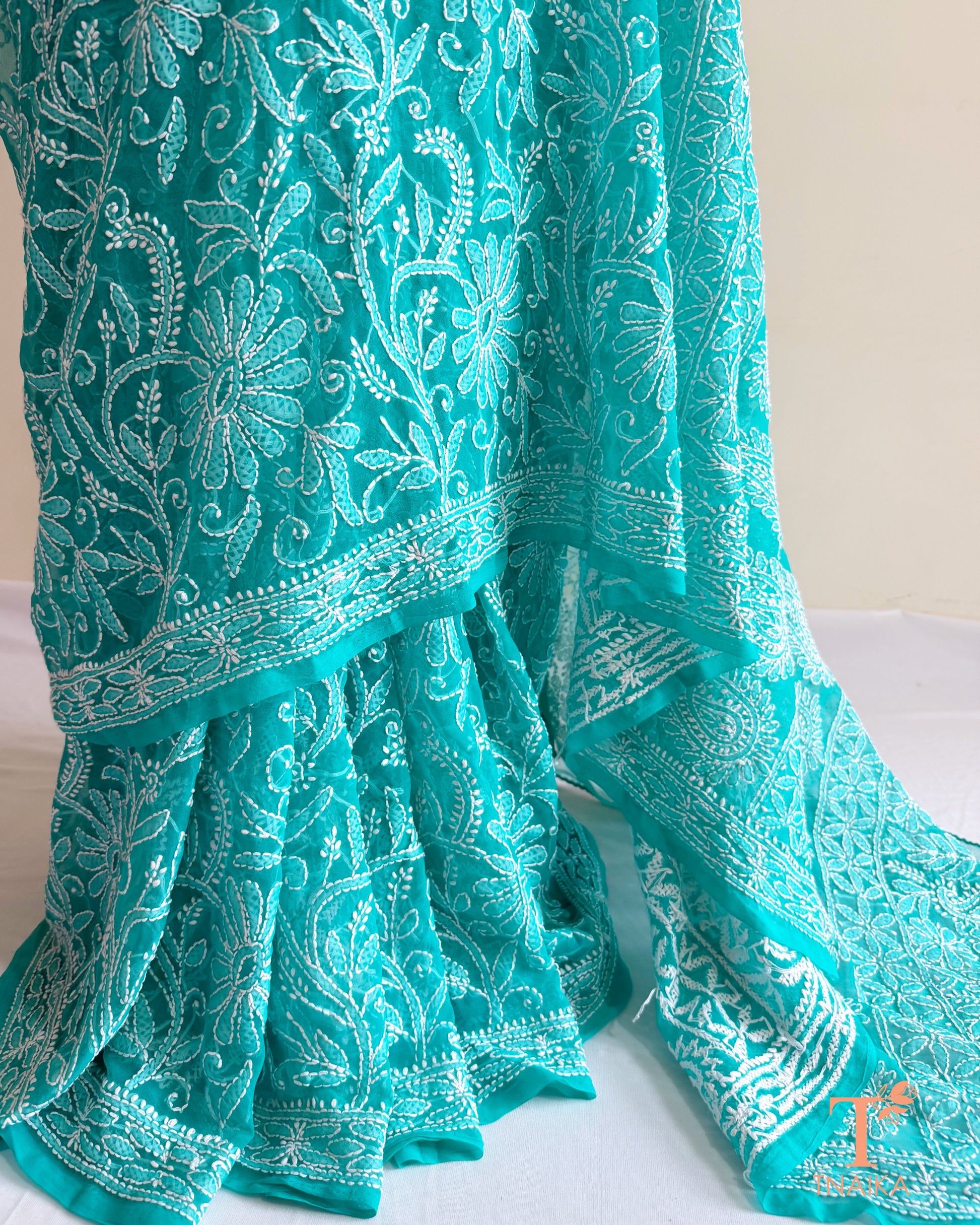 Elegant turquoise teal Chikankari saree featuring detailed white floral embroidery and embroidered border.