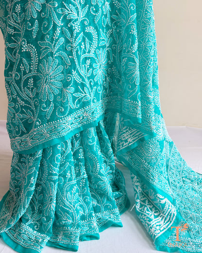 Elegant turquoise teal Chikankari saree featuring detailed white floral embroidery and embroidered border.