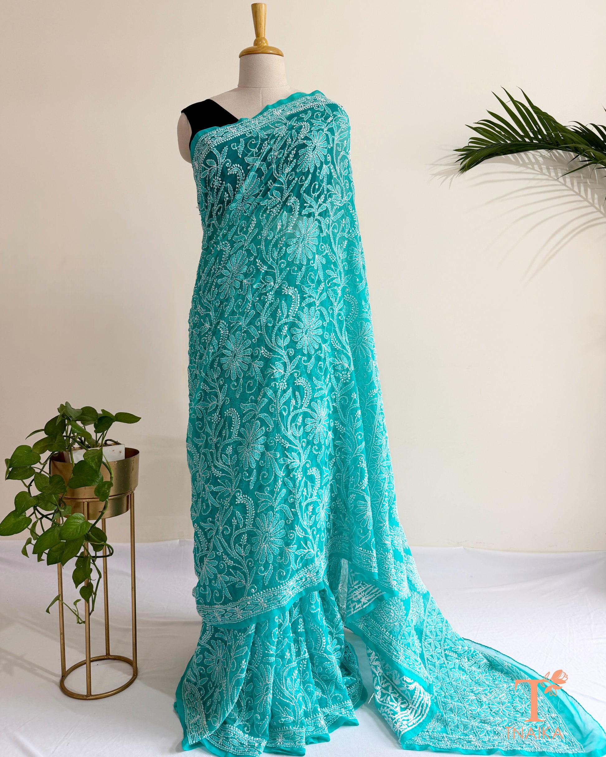 Turquoise teal Chikankari saree with intricate white Lucknowi hand embroidery and floral vine patterns.