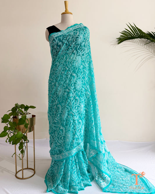 Turquoise teal Chikankari saree with intricate white Lucknowi hand embroidery and floral vine patterns.