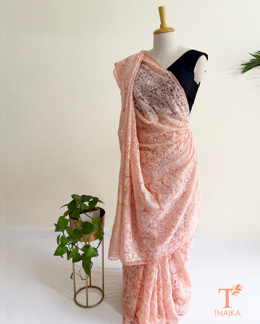 Premium blush pink Lucknowi Chikankari saree featuring handcrafted white floral embroidery and richly embroidered pallu.