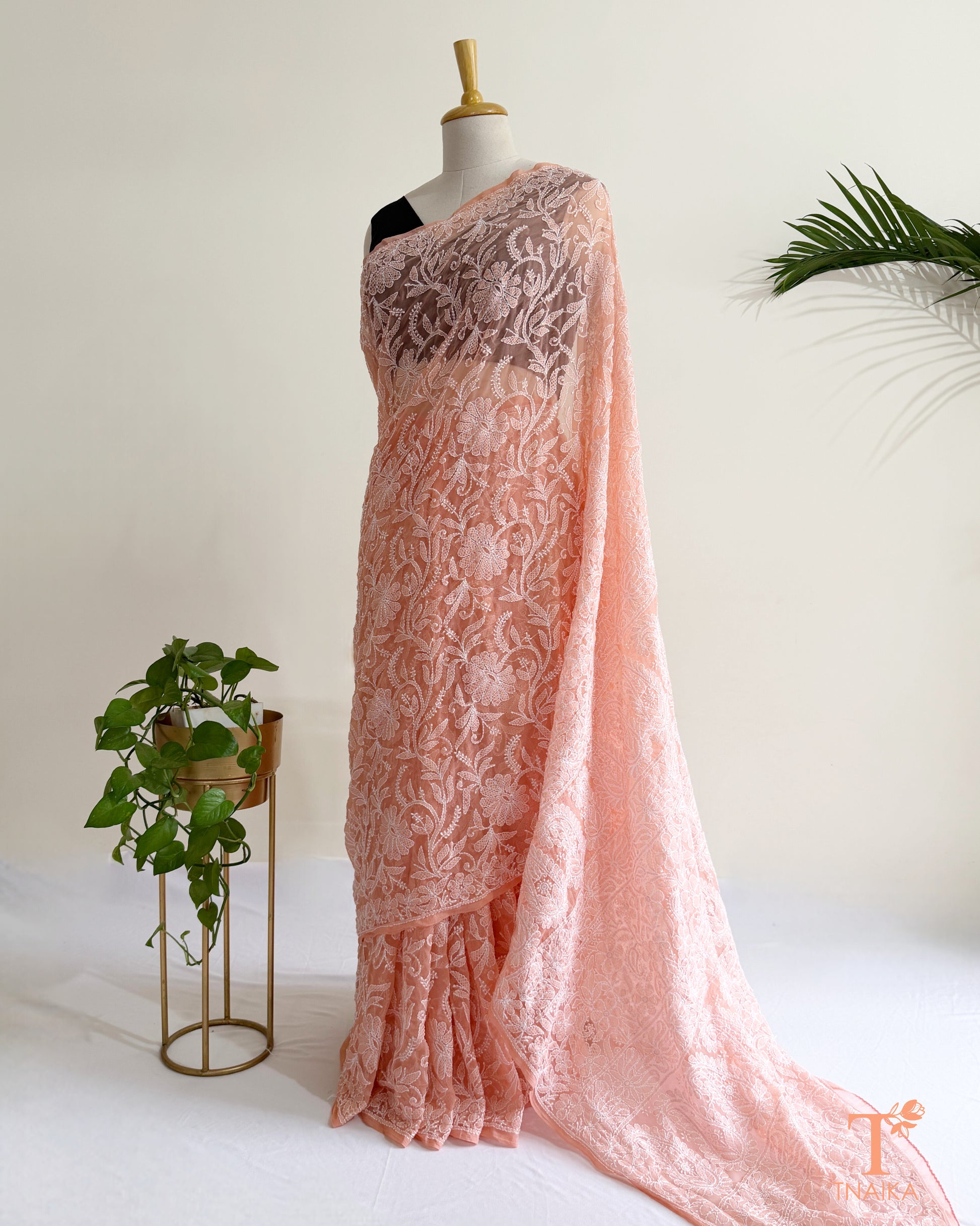 Blush pink Chikankari saree with intricate white Lucknowi hand embroidery and elegant floral vine patterns.