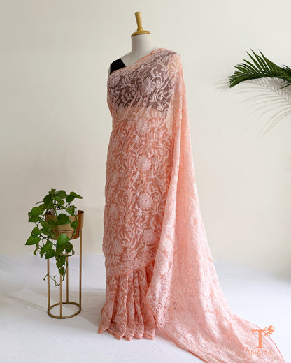 Blush pink Chikankari saree with intricate white Lucknowi hand embroidery and elegant floral vine patterns.