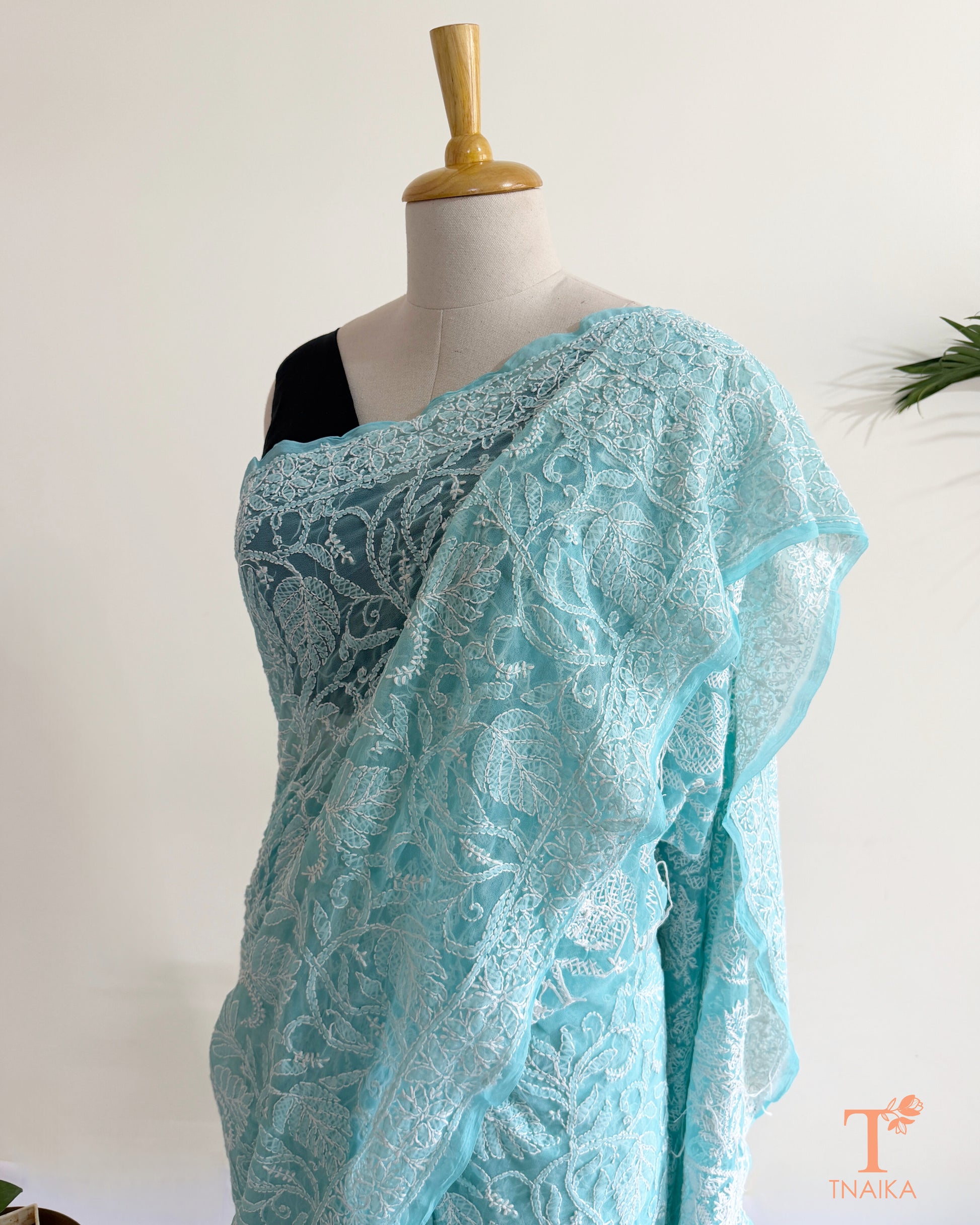 Pastel aqua blue Chikankari saree with exquisite white embroidery, floral vines, and elegant border detailing.