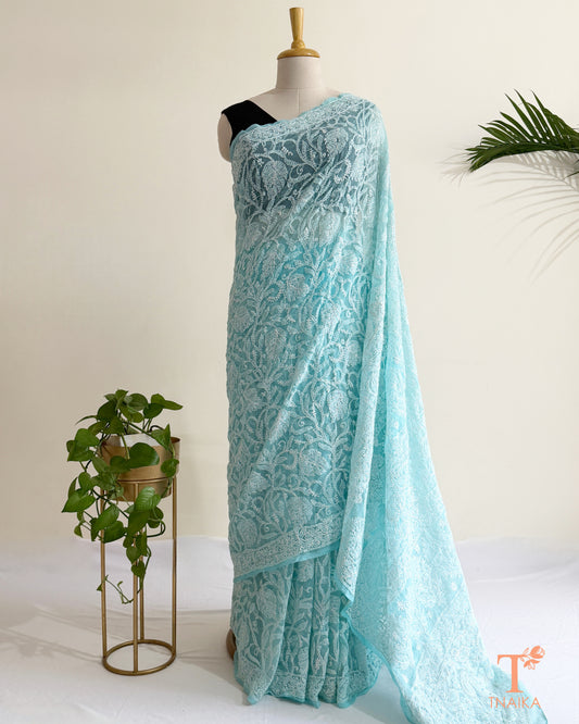Aqua blue Chikankari saree with intricate white Lucknowi hand embroidery and elegant floral vine patterns.