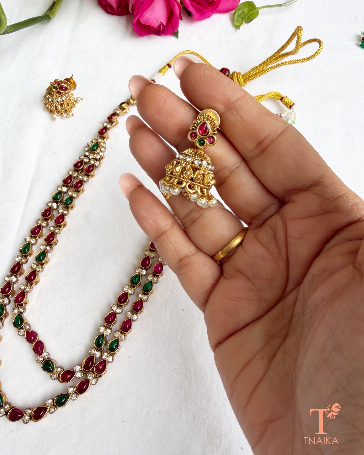 Dual-layer green teardrop stone necklace set with gold polish and traditional jhumki earrings.