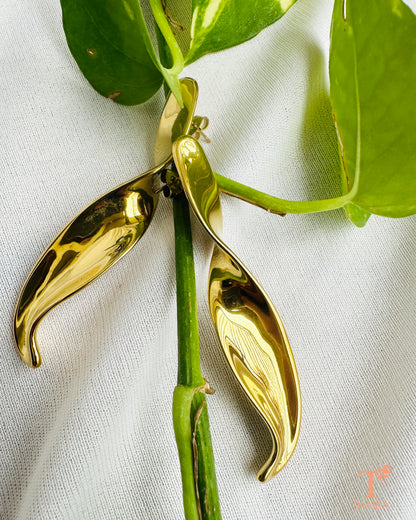 Close-up of modern gold drop earrings with a sleek polished finish.