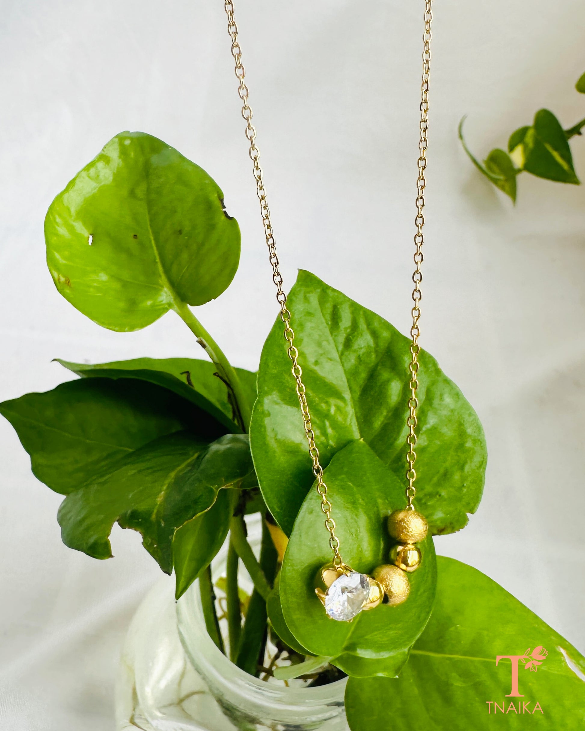 Gold tone anti-tarnish necklace with a sparkling crystal centerpiece and delicate bead detailing.