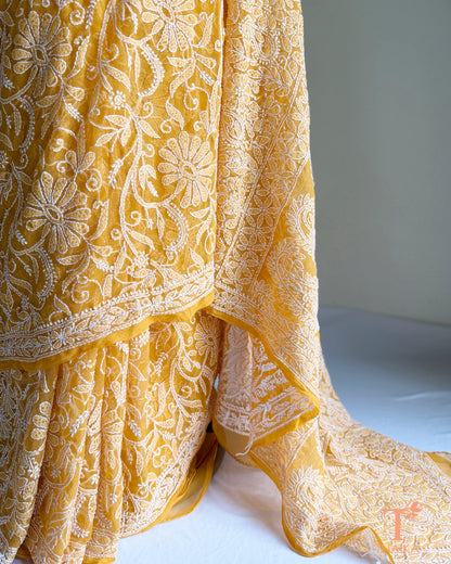 Mustard Yellow Chikankari georgette saree with intricate white floral embroidery.