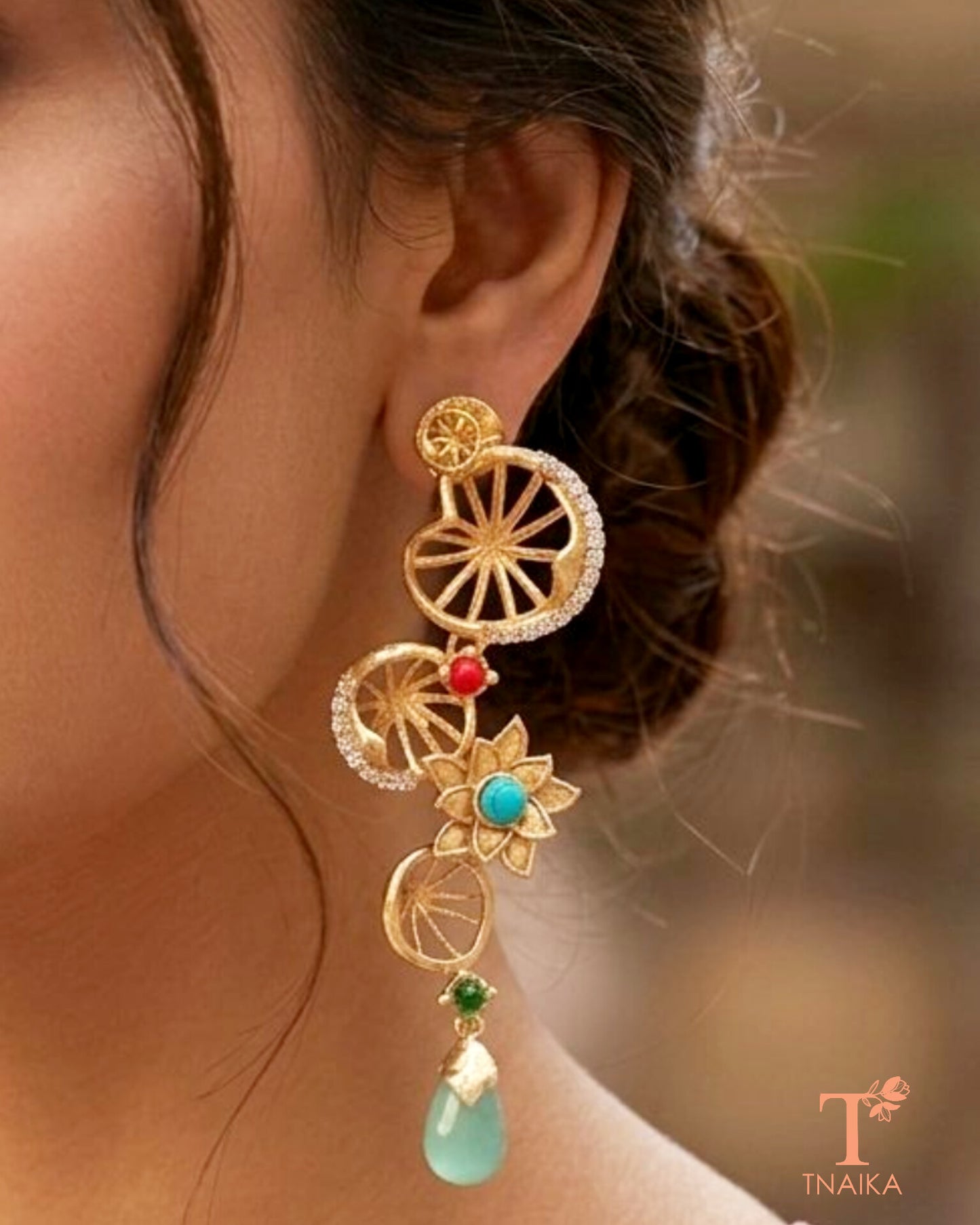 Statement brass dangler earrings featuring AD stones and decorative floral accents.