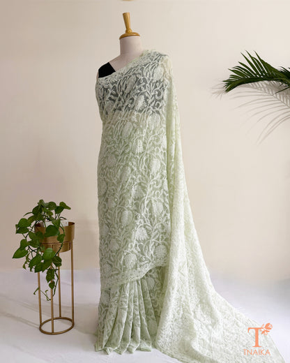 Mint green Chikankari saree with intricate white Lucknowi hand embroidery and elegant floral vine patterns.